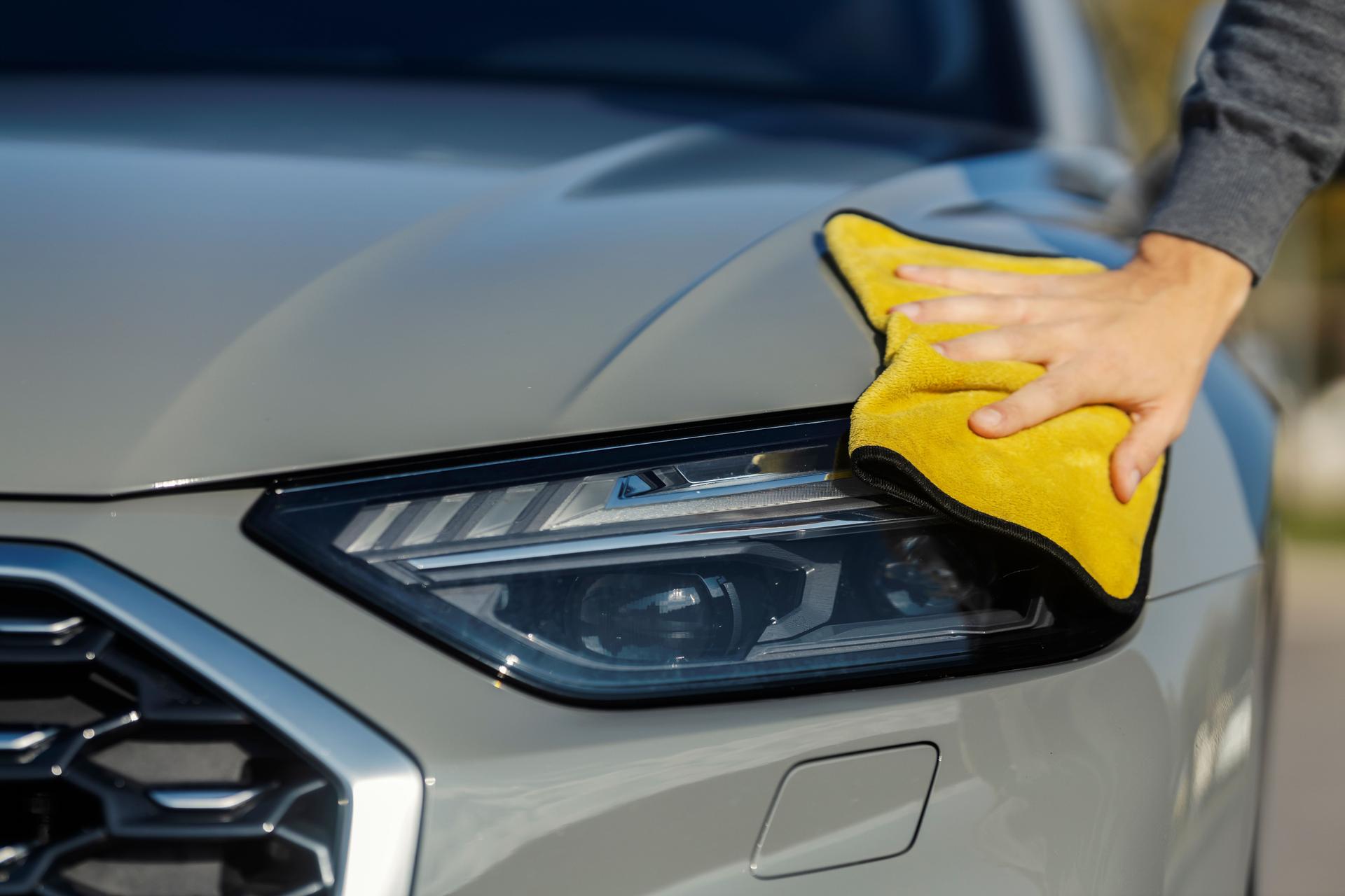 Close up of a male's hand cleaning car headlights at self service car wash.